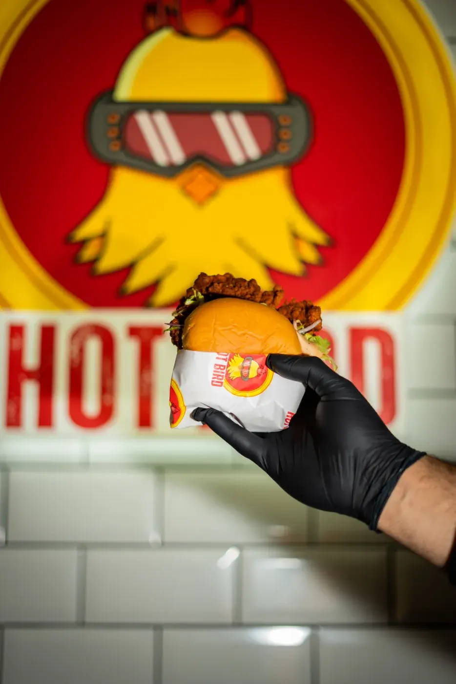 Hot Bird fillet sandwich in front of the mascot mural